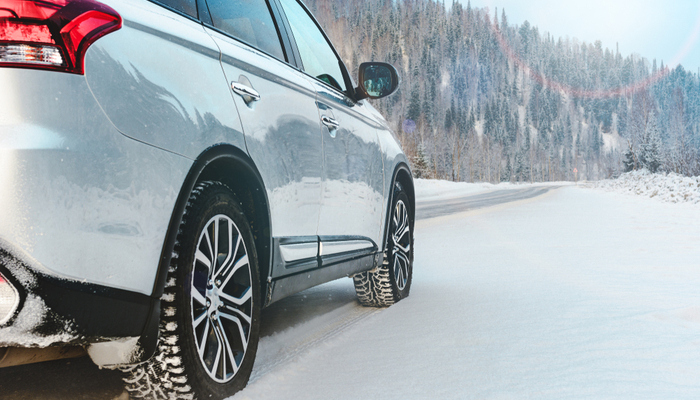 White shiny modern suv car on the roadside of winter snowy road in the mountain