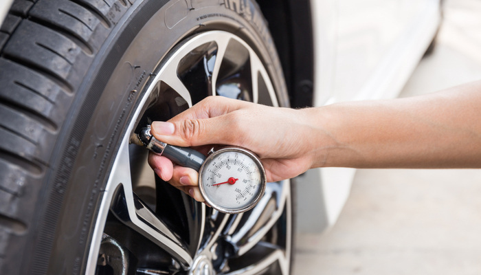 Close-Up Of a male hand holding pressure gauge for car tire pressure measurement
